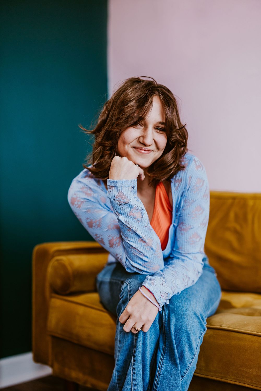 Casual indoor photoshoot on a brown couch wearing denim and displaying playful expressions.