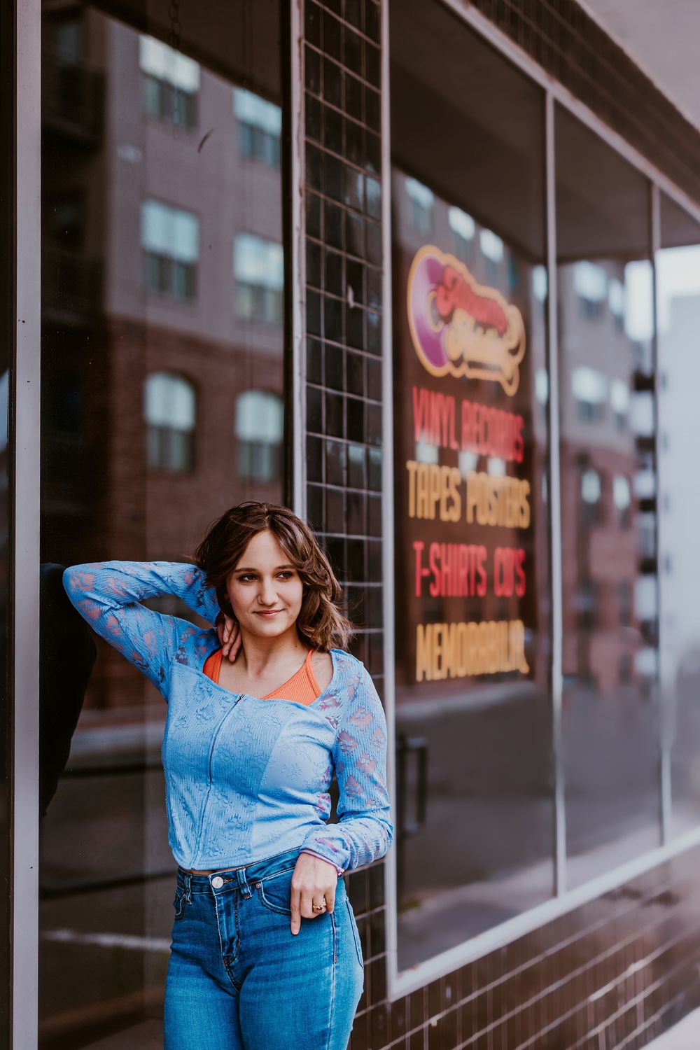 Urban portrait session against storefront windows wearing denim and showing casual poses.