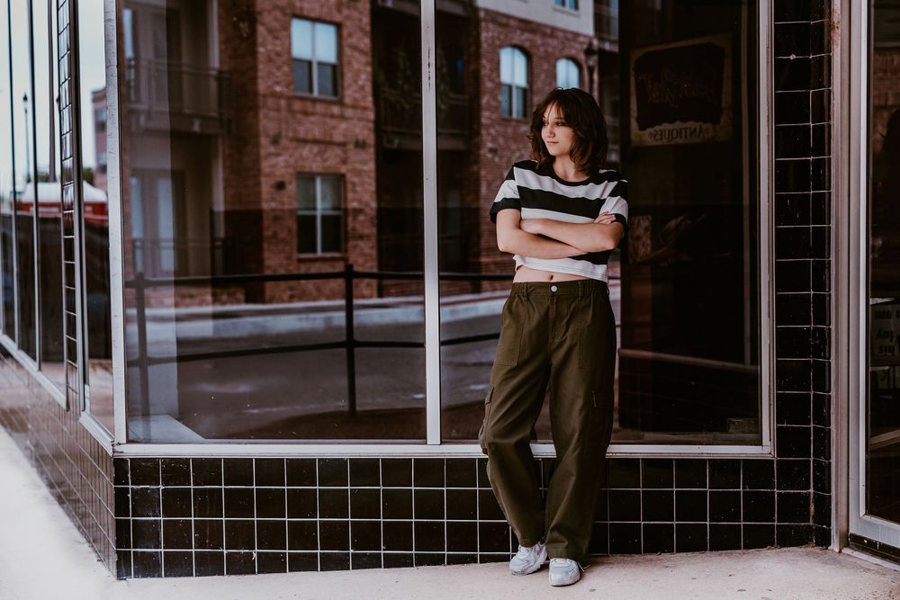 Urban photography session outside brick building with reflective windows.