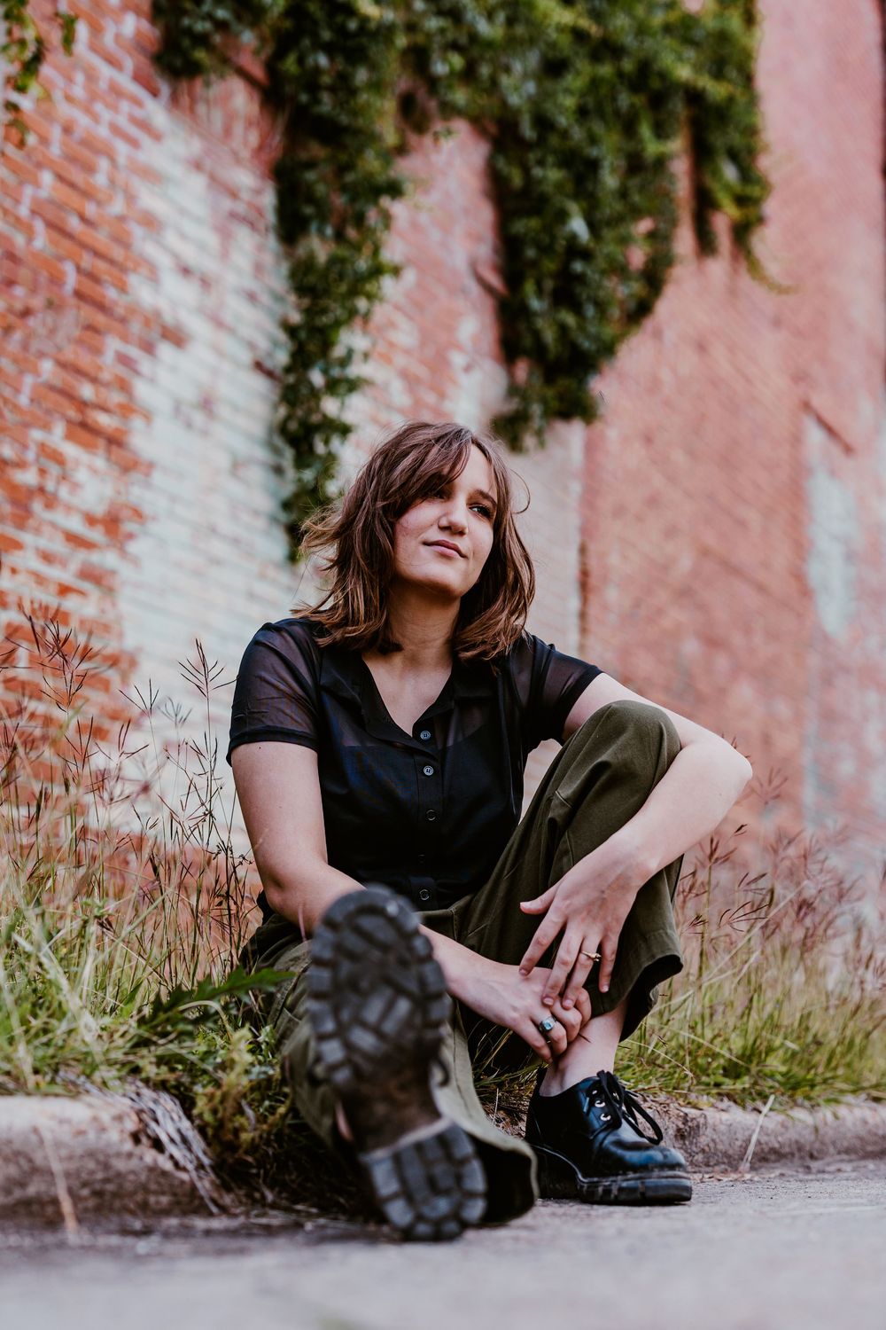 Casual outdoor portrait session against brick wall with ivy and natural lighting.