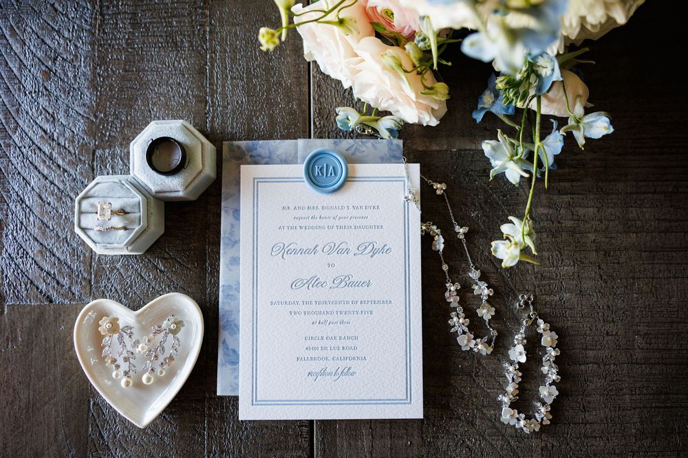 Wedding invitation suite with floral details and elegant calligraphy displayed on dark wooden surface.