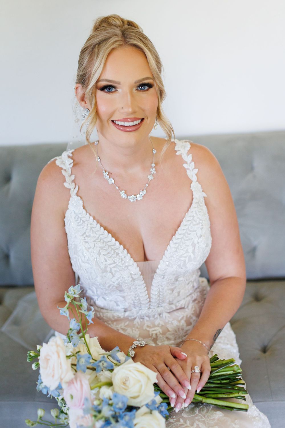 Close-up details of a white lace wedding dress with delicate beading and floral bouquet.