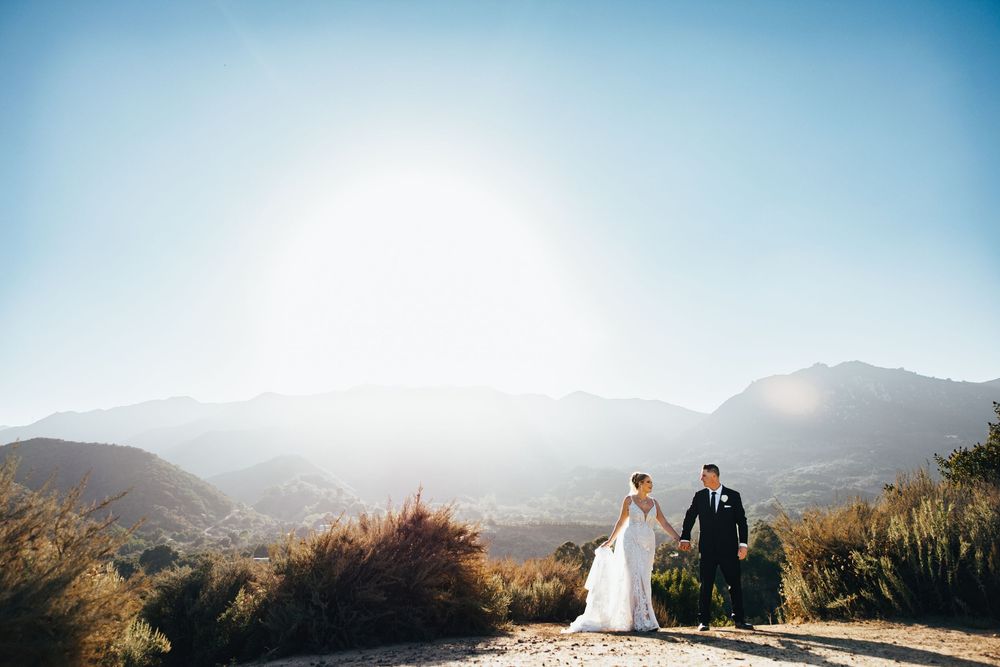 Panoramic mountain landscape with dramatic sunlight streaming through misty peaks and golden desert vegetation.