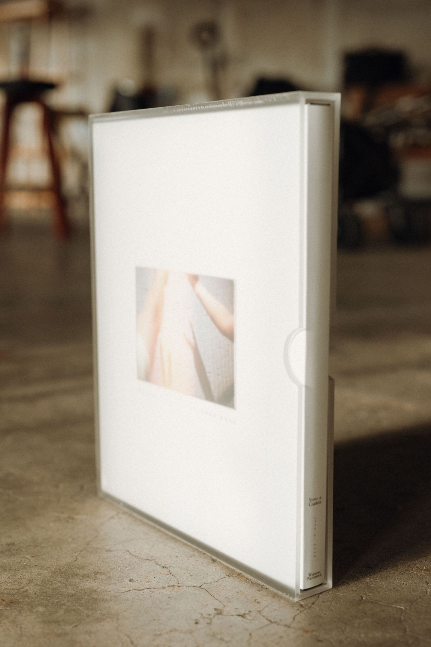 A series of white photo albums or books arranged in a diagonal line on a concrete floor, showing varying angles and depths.