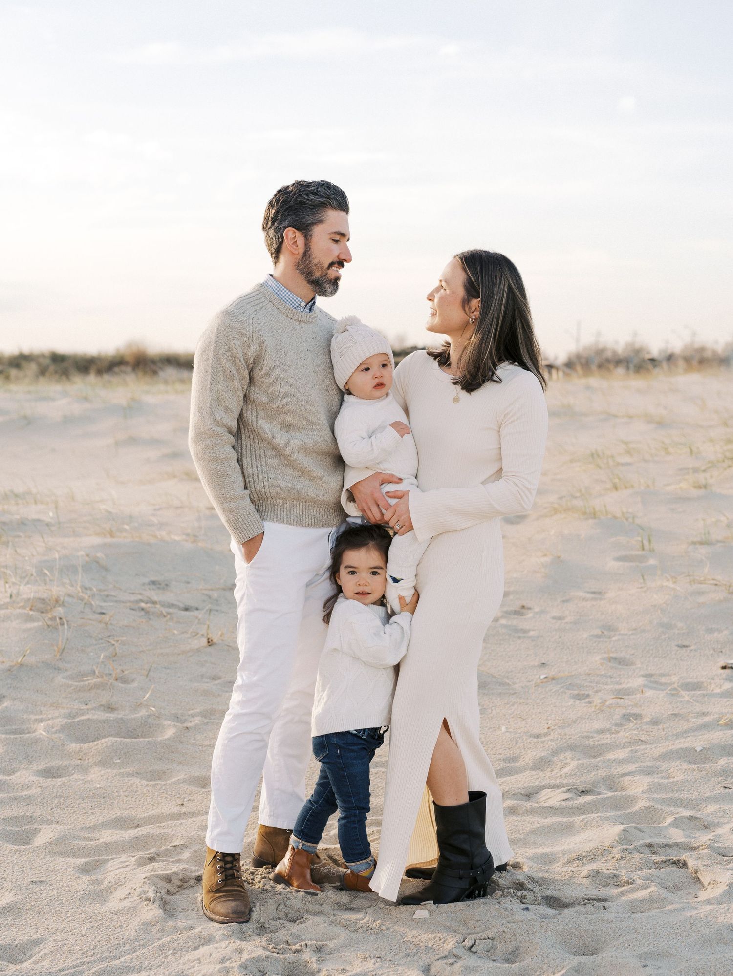 Family laughing together near the dunes during a fall beach photo session in New Jersey.