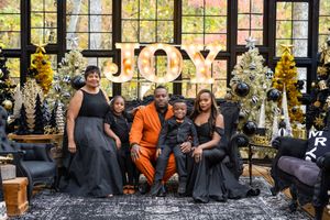 a family of 5 elegantly dressed sitting on a couch in a black and gold greenhouse for the Christmas holiday