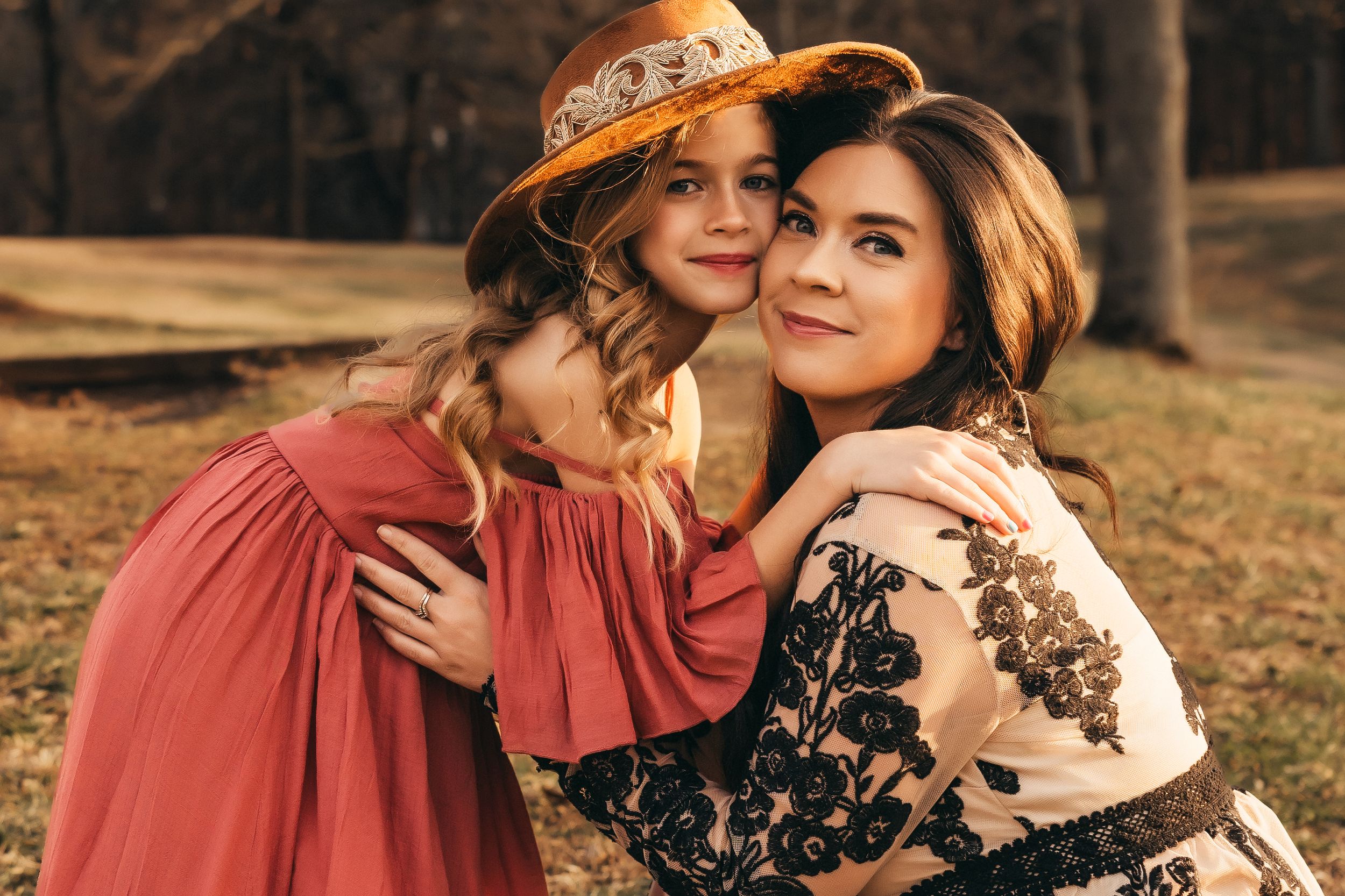 A mother and daughter during sunset. The mom has bent down to the daughter's face