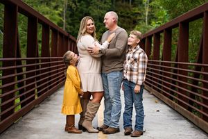 A family of four standing looking at each other on a large metal bridge