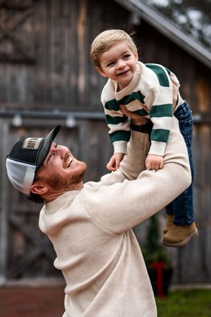 a dad lifting his small toddler in the air like an airplane