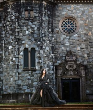 Lady in a formal black dress standing on steps in front of a rock cathedral building