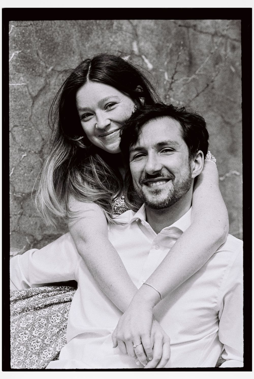 Close up portrait of her sitting behind him with her arms wrapped around his neck. They both look at the camera smiling together in Maine.