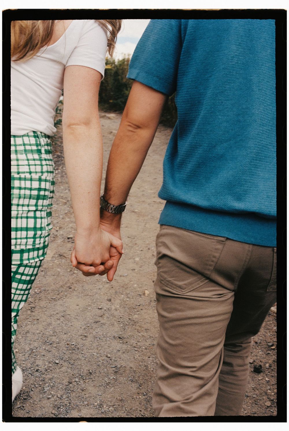 Couple holds hands while walking together at Fort Williams park in Cape Elizabeth, Maine. She wears vintage style clothing on 35mm film.