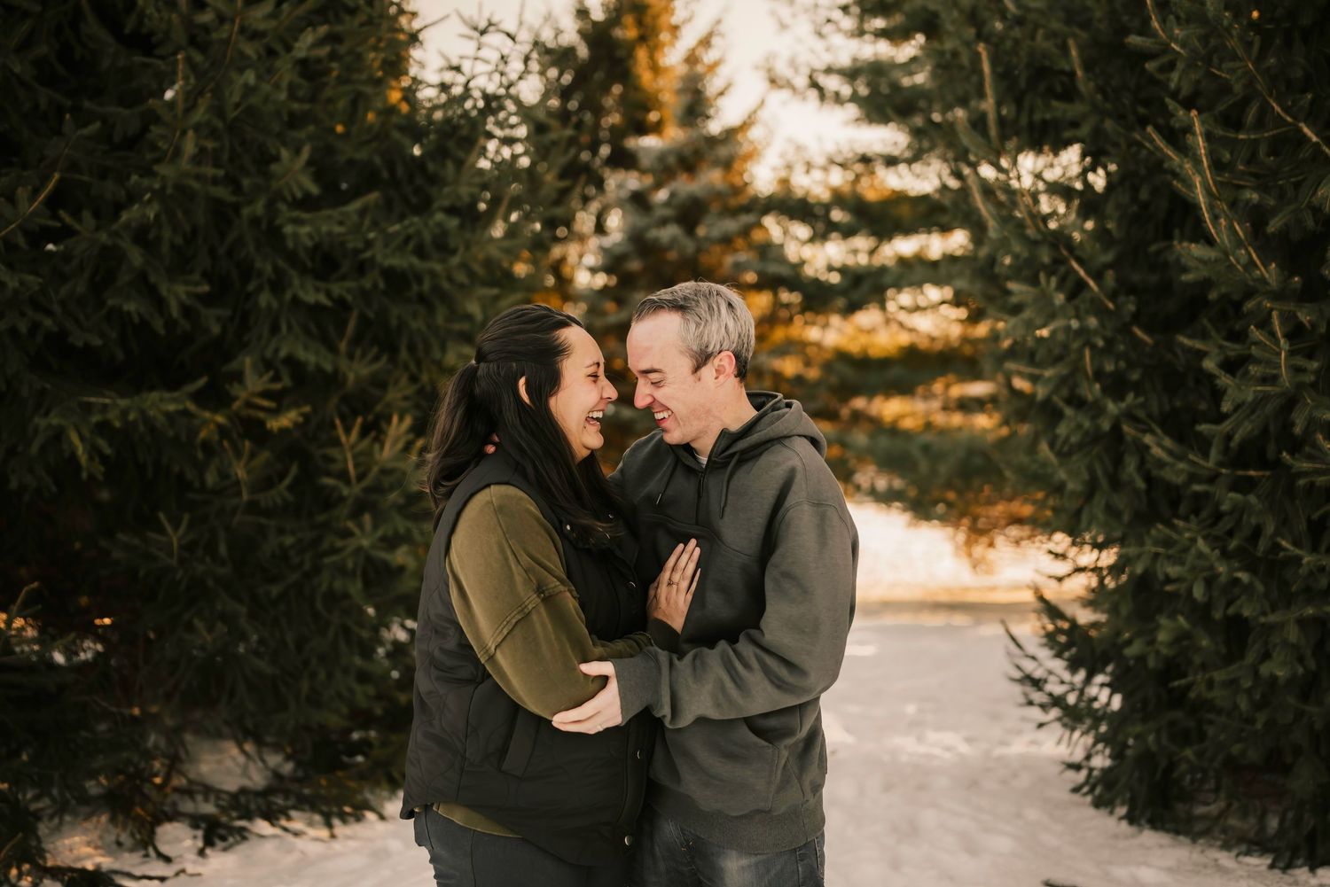 husband and wife laugh together during their family photo session at French park