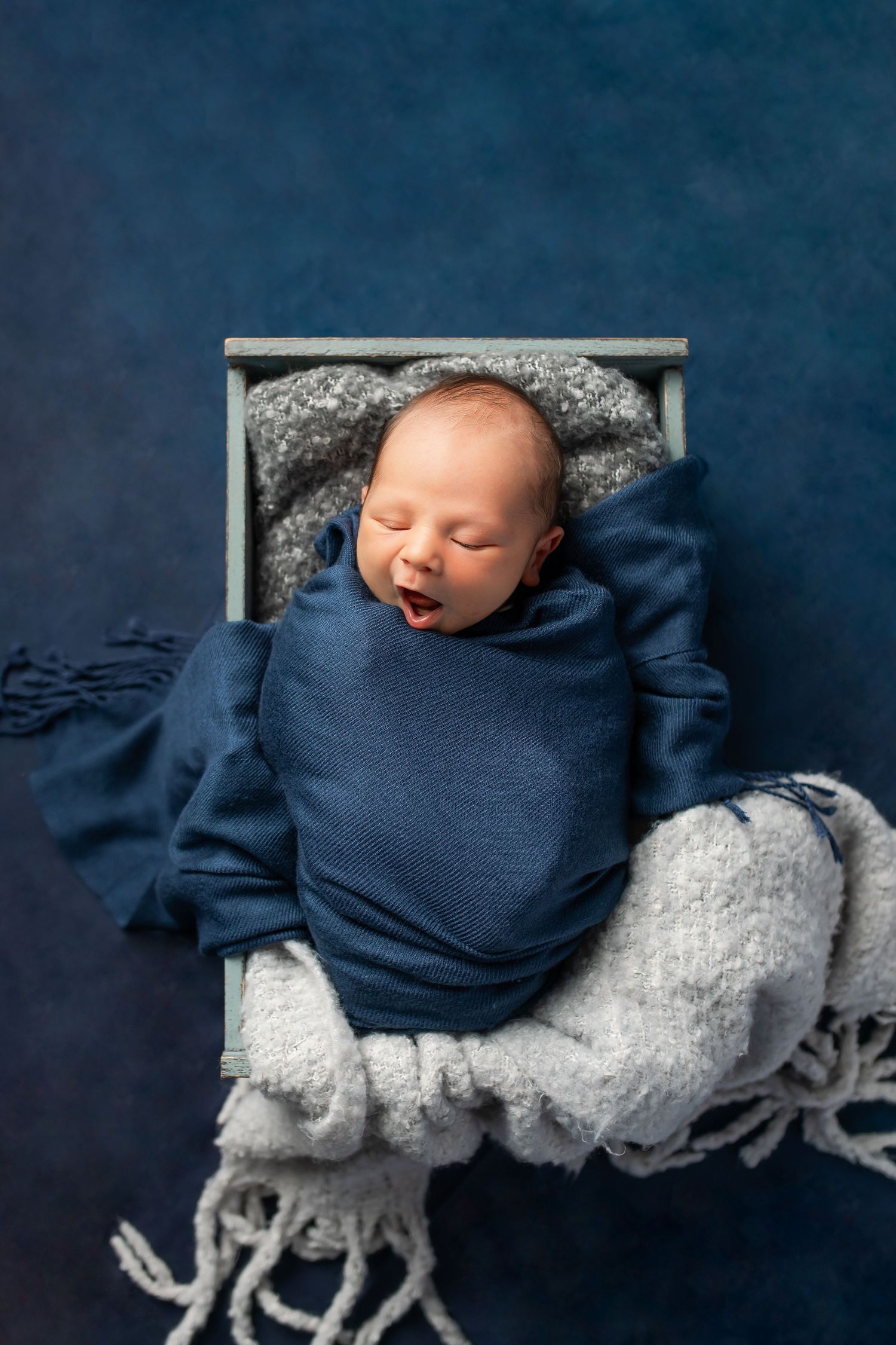Peaceful newborn baby sleeping curled up on soft cream backdrop during a newborn studio session.