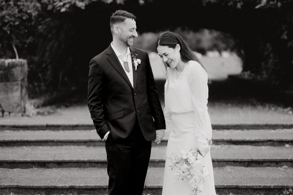 Newlywed couple shares a candid laughing moment together on their wedding day, captured by Apertured Media Auckland Wedding Photographer.
