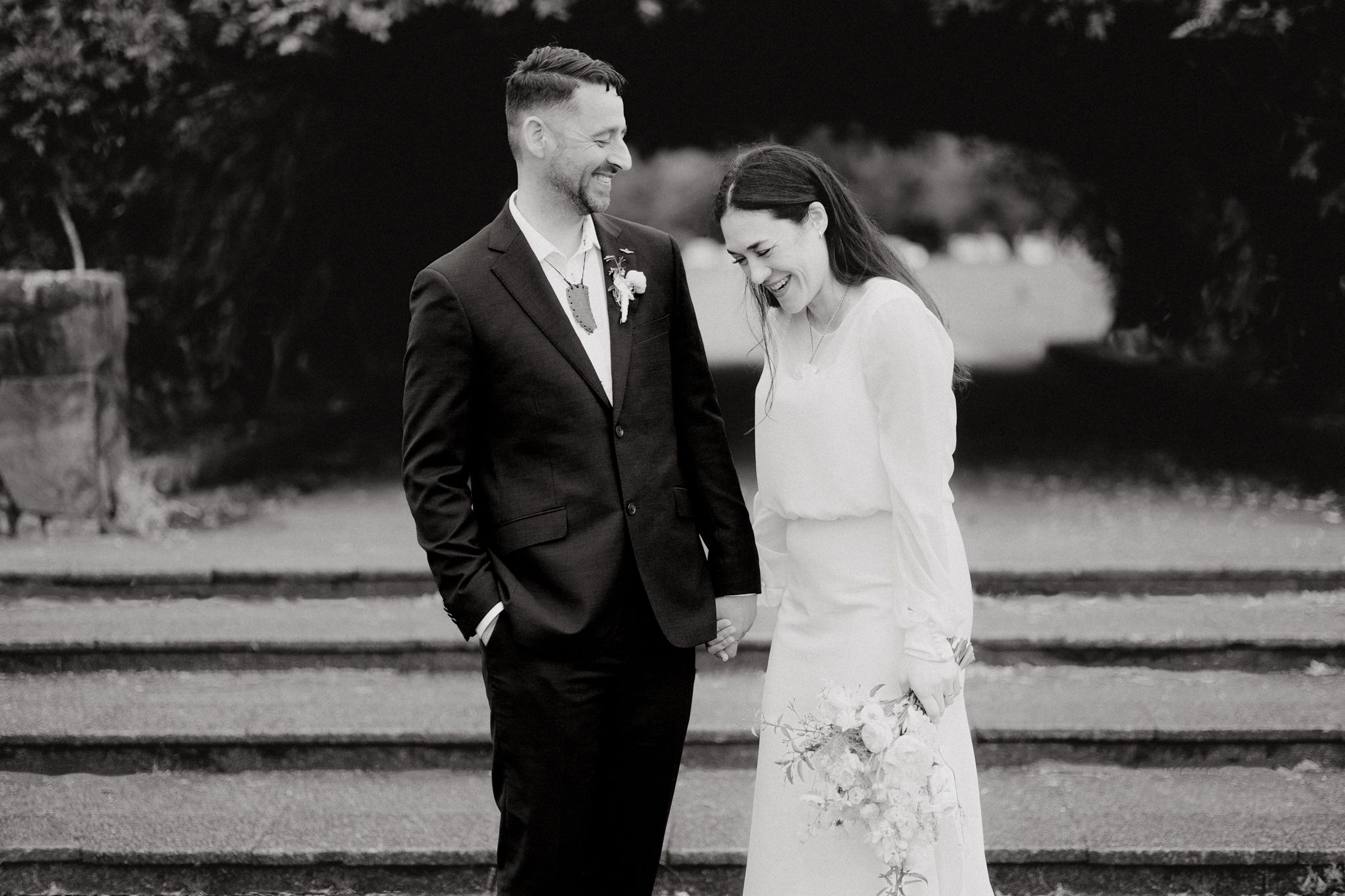 Newlywed couple shares a candid laughing moment together on their wedding day, captured by Apertured Media Auckland Wedding Photographer.