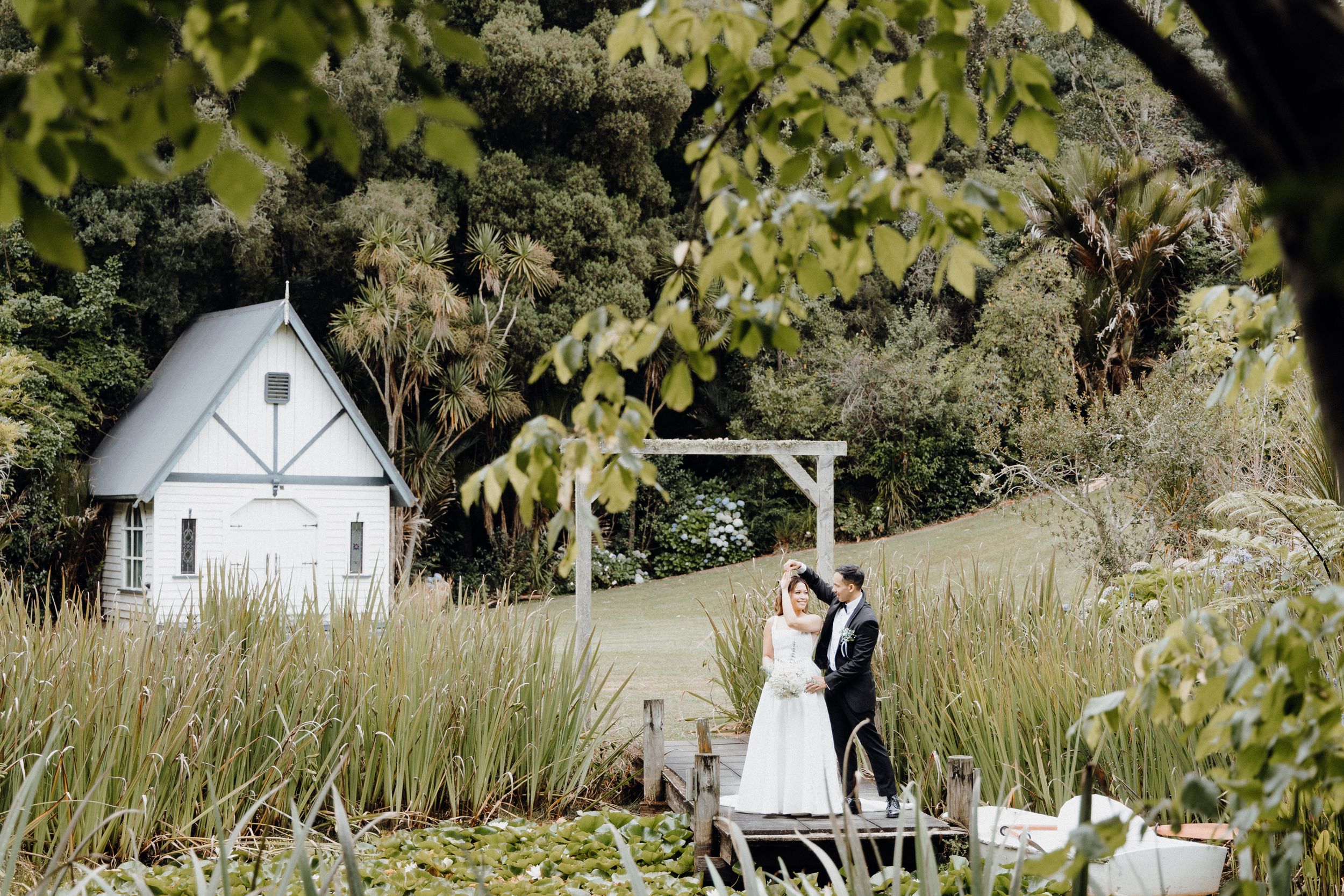 A couple celebrates their wedding on a rustic wooden deck captured by Apertured Media Auckland Wedding Photographer