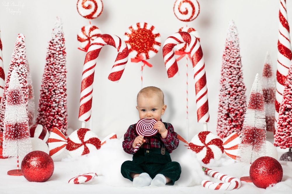 A festive holiday scene with candy canes, red ornaments, and bottle brush Christmas trees against a white background.