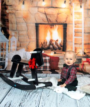 Holiday scene with rocking horse and cozy fireplace on white wooden floor.