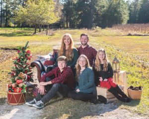 Outdoor family portrait with Christmas decor and wooden crates in natural setting.