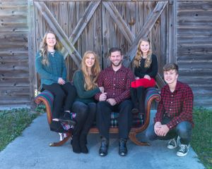 Group photo in casual attire against wooden barn door background.