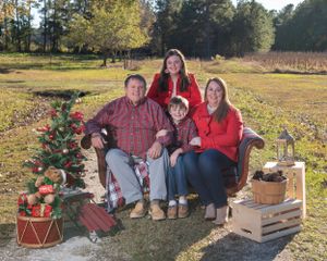 Holiday outdoor portrait with decorated Christmas tree and wooden crates on sunny field.