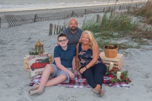 Beach photo session with a small group on blanket surrounded by holiday decorations at sunset.