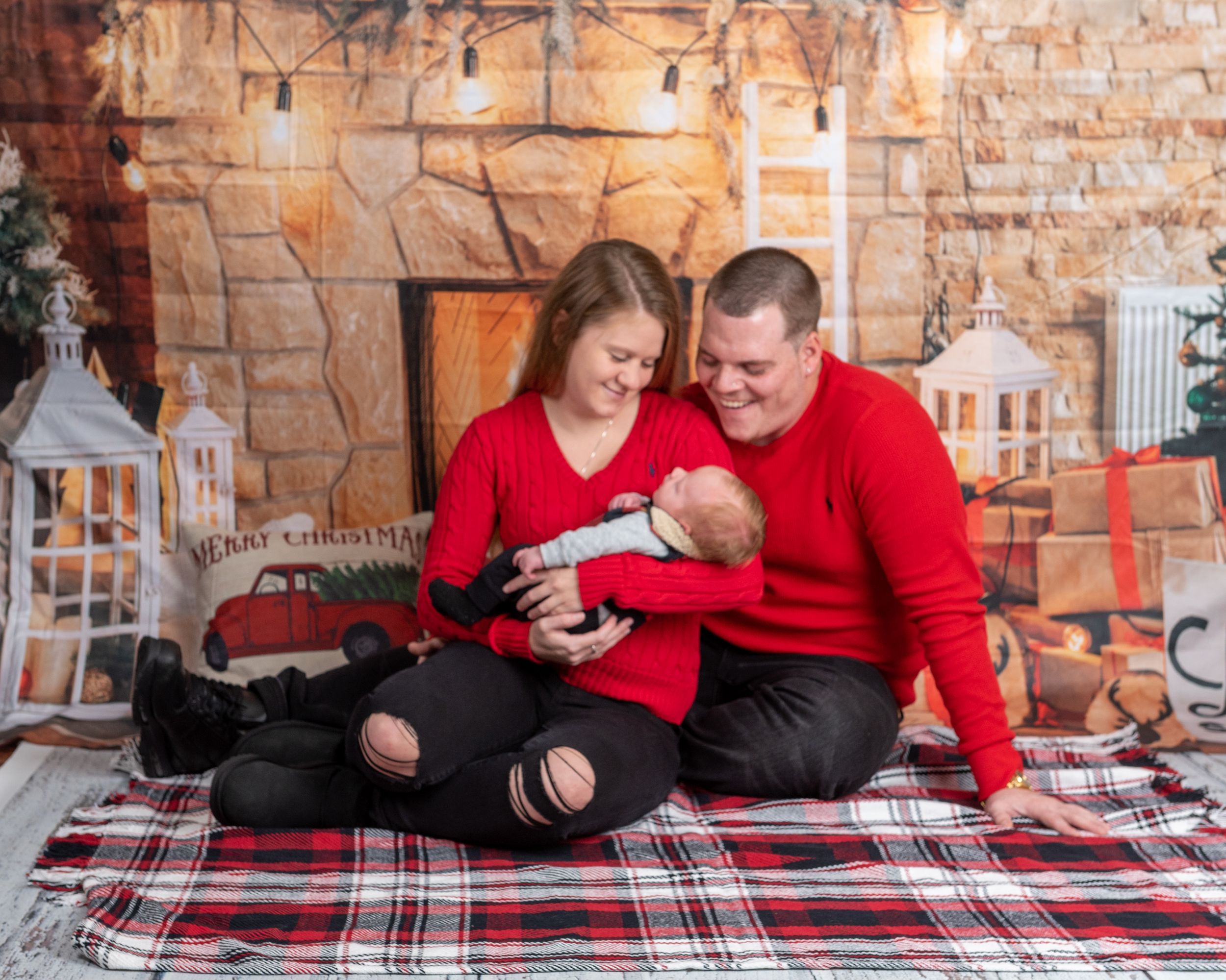 Cozy indoor holiday scene with couple on plaid blanket in brick room with lantern decorations.