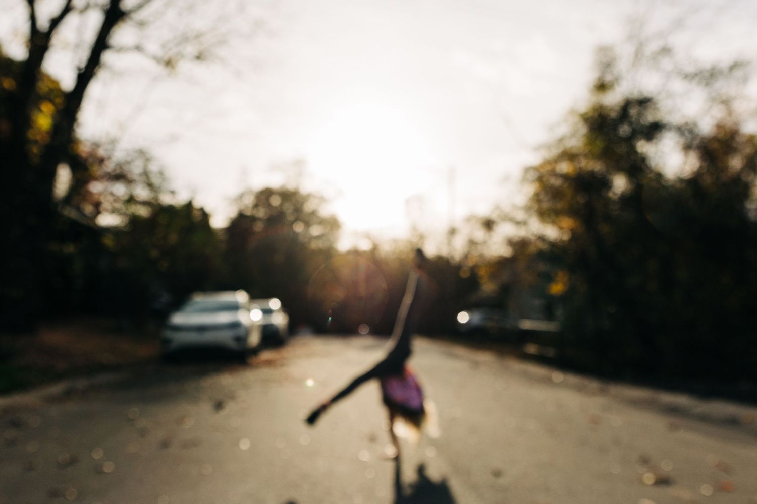 Silhouetted figure of a young girl doing a cartwheel on a street at sunset with warm golden lighting in Charlotte, NC