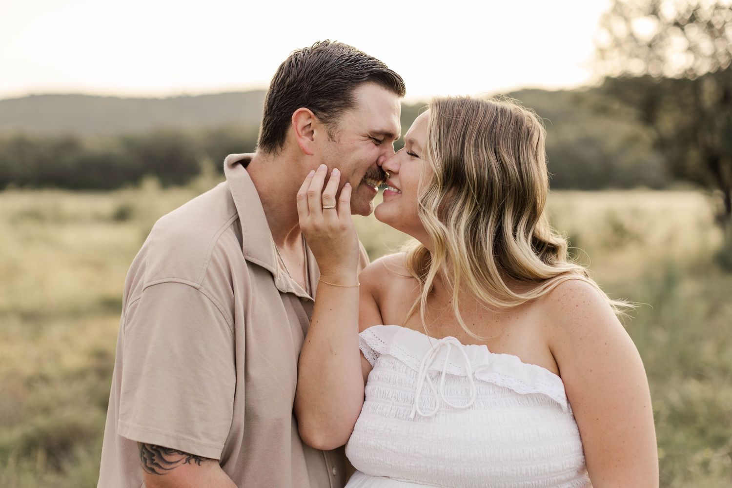 A romantic sunset photoshoot in a golden field captures tender moments between a couple at golden hour, by best San Antonio Photographer.
