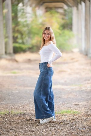 Casual portrait series showing someone in denim and white top posing under a covered walkway.