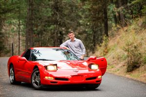 Bright red Ferrari sports car parked on a winding forest road.