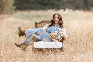 Person in cowboy boots lying in golden grass field during sunset with dreamy ethereal lighting effect.