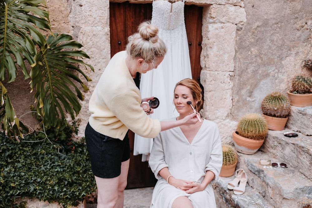 La Chia gibt einer Braut, im Innenhof der Finca Xiclati auf Mallorca, mit Kakteen in Töpfen den letzten Schliff.