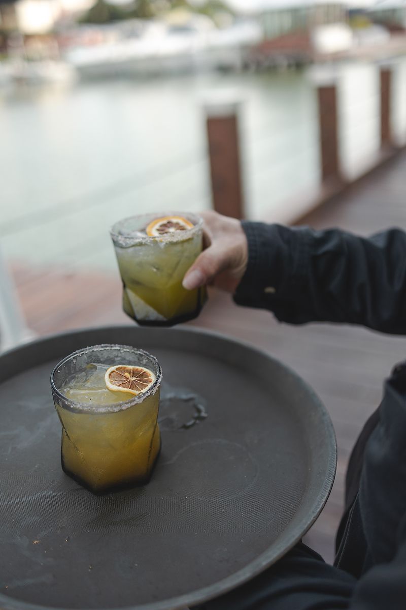 Citrus cocktails being served on dark plates against an outdoor backdrop.