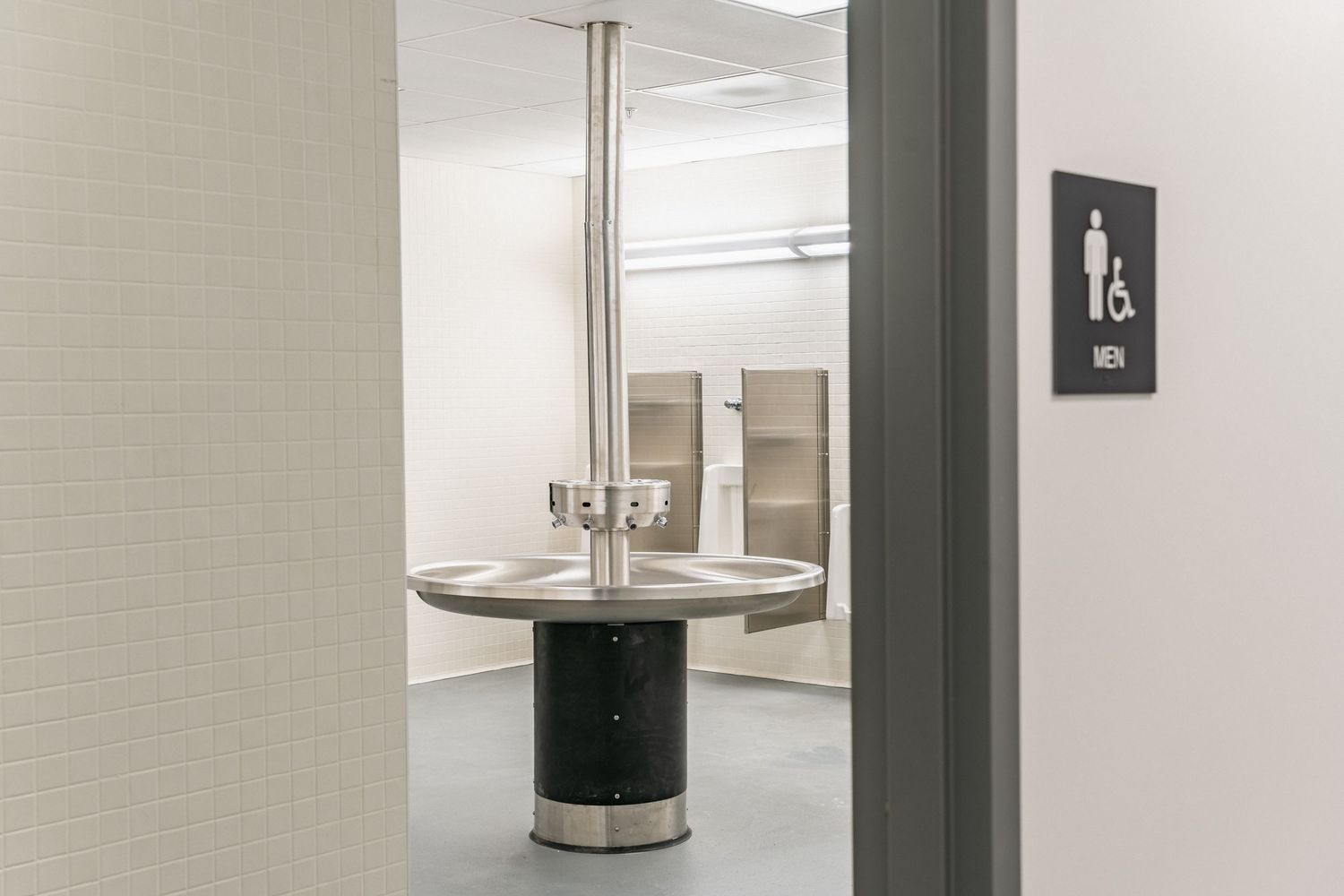 Modern commercial bathroom entrance with circular washing station and minimalist design.