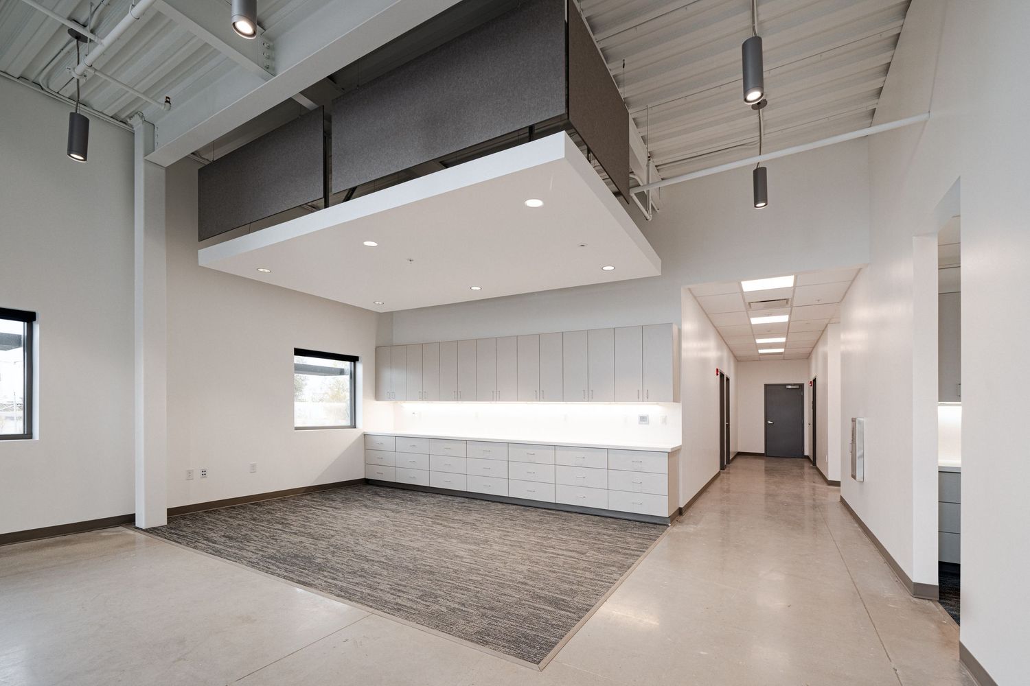 Modern white office space interior with high ceilings, track lighting and polished concrete floors.