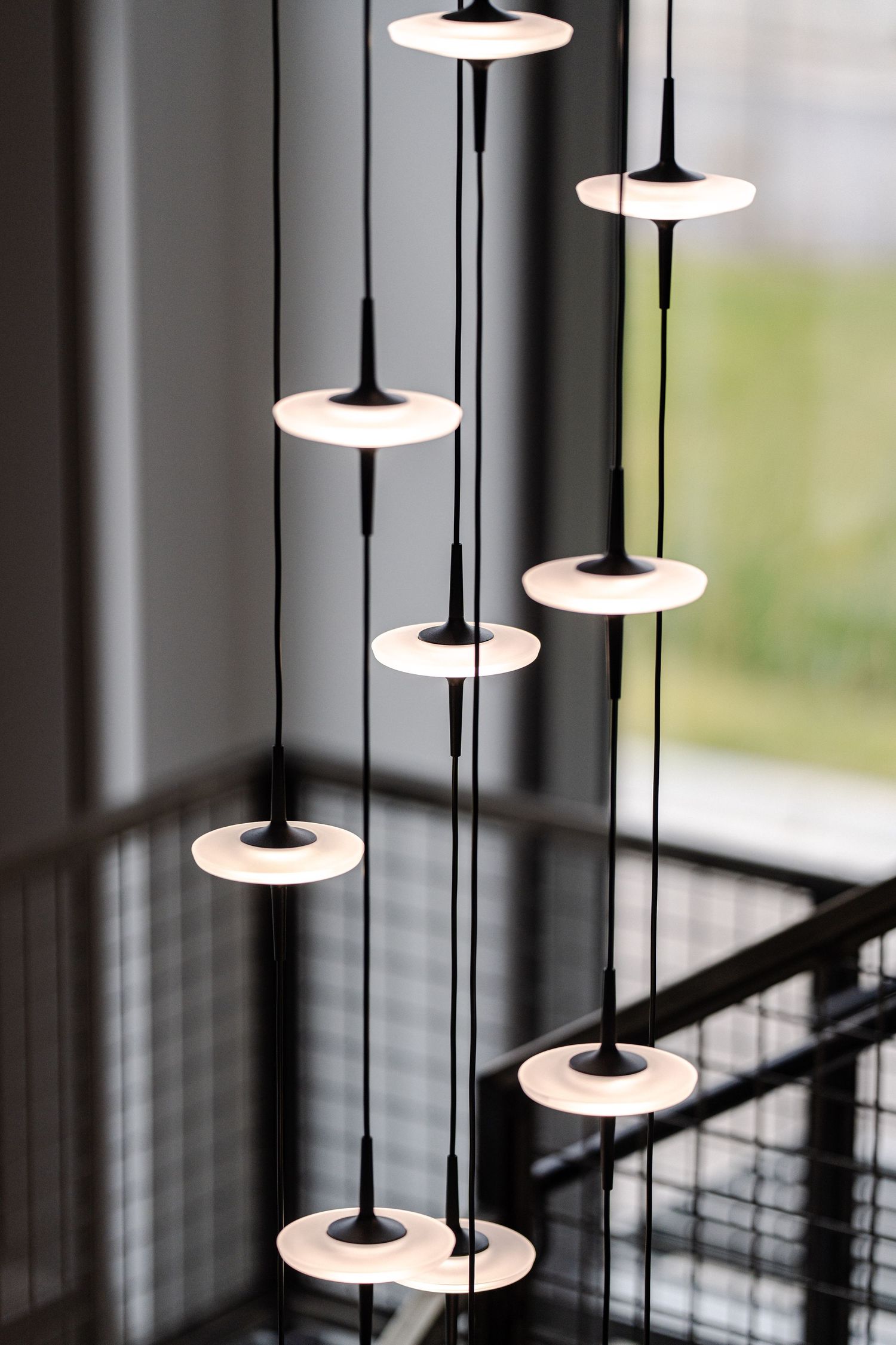 Modern pendant lights with disc-shaped shades hanging at different heights create a stylish minimalist lighting display.