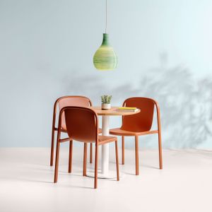 Modern dining set with orange chairs and round table under a mint green pendant light.