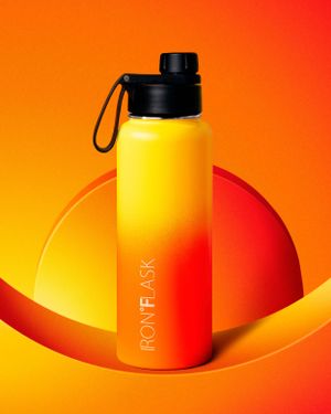 Yellow and orange gradient water bottle photographed against vibrant sunset-colored background.