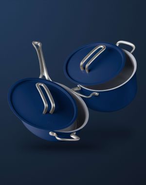 Two floating blue cookware pans with silver handles against dark background.