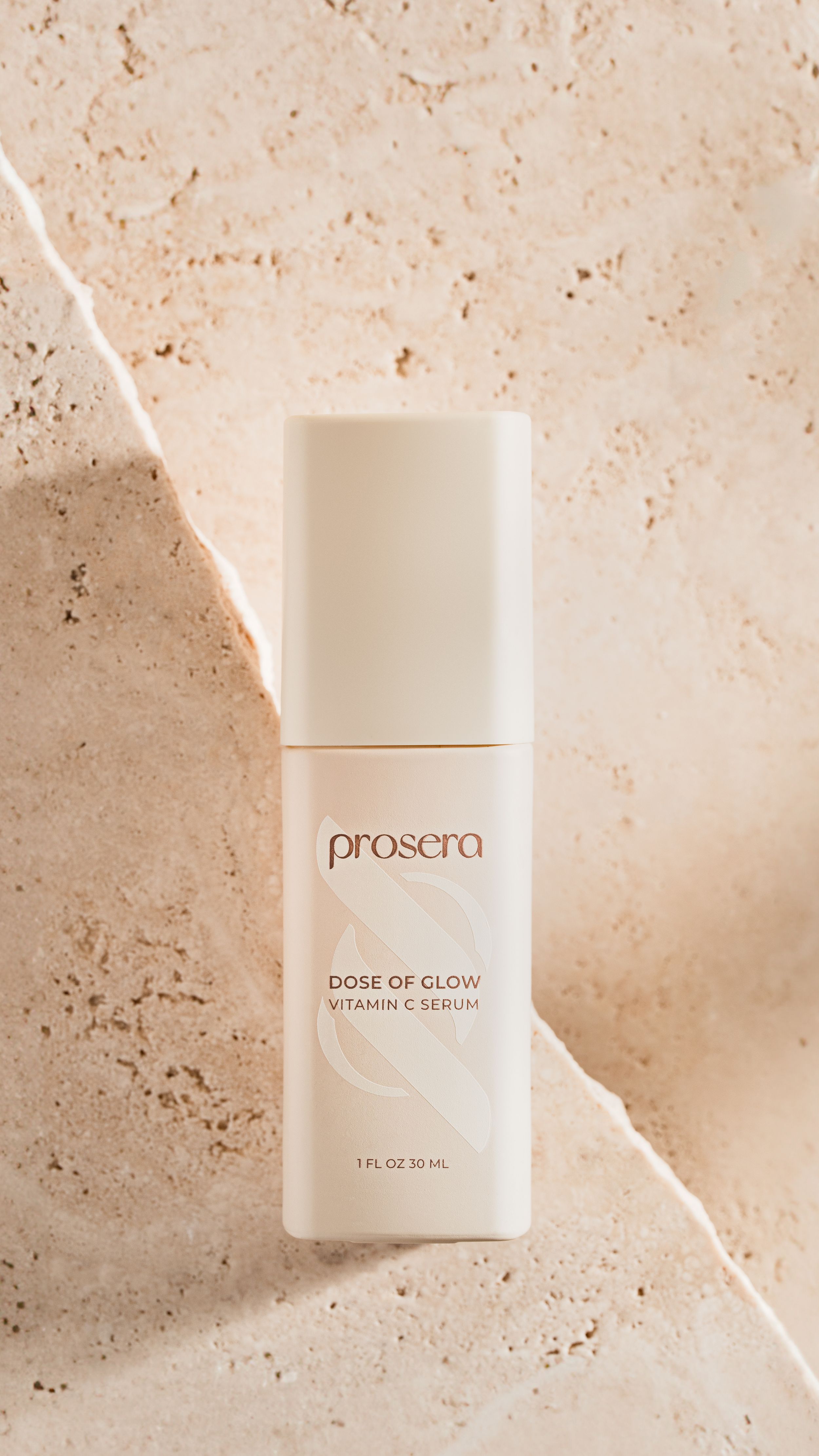 Minimalist white cosmetic skincare serum bottles arranged on textured beige marble background with natural lighting.