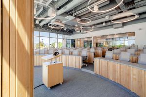 Modern open office space with wooden furniture and exposed ceiling infrastructure.