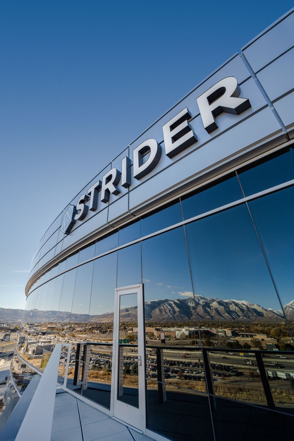 Close-up panoramic view of shiny chrome letters spelling 'DREYER' mounted on a reflective surface with mountains in background.