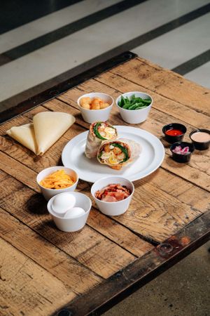 Mexican style burrito plate with various dips and condiments on rustic wooden table.