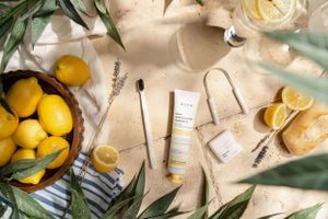 Flatlay of skincare products with fresh lemons and botanical elements on beige background.