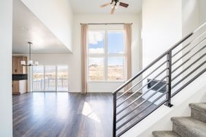 Modern apartment interior with high ceiling, horizontal railings, and large window with mountain views.