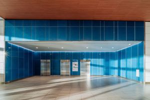 Modern lobby interior with blue glass walls and elevator entrance.