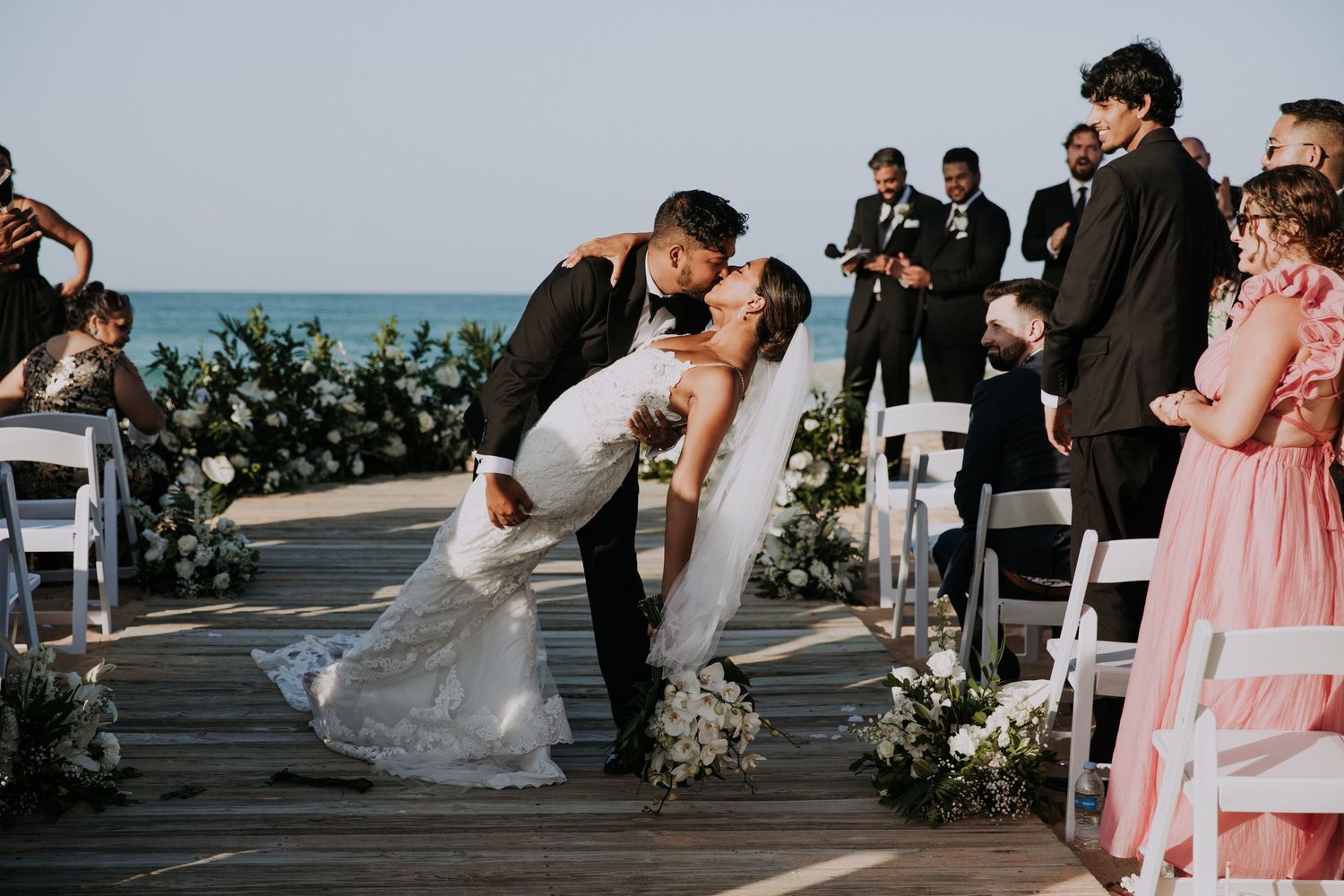 Elegant beach wedding setup with white chairs and ocean views.