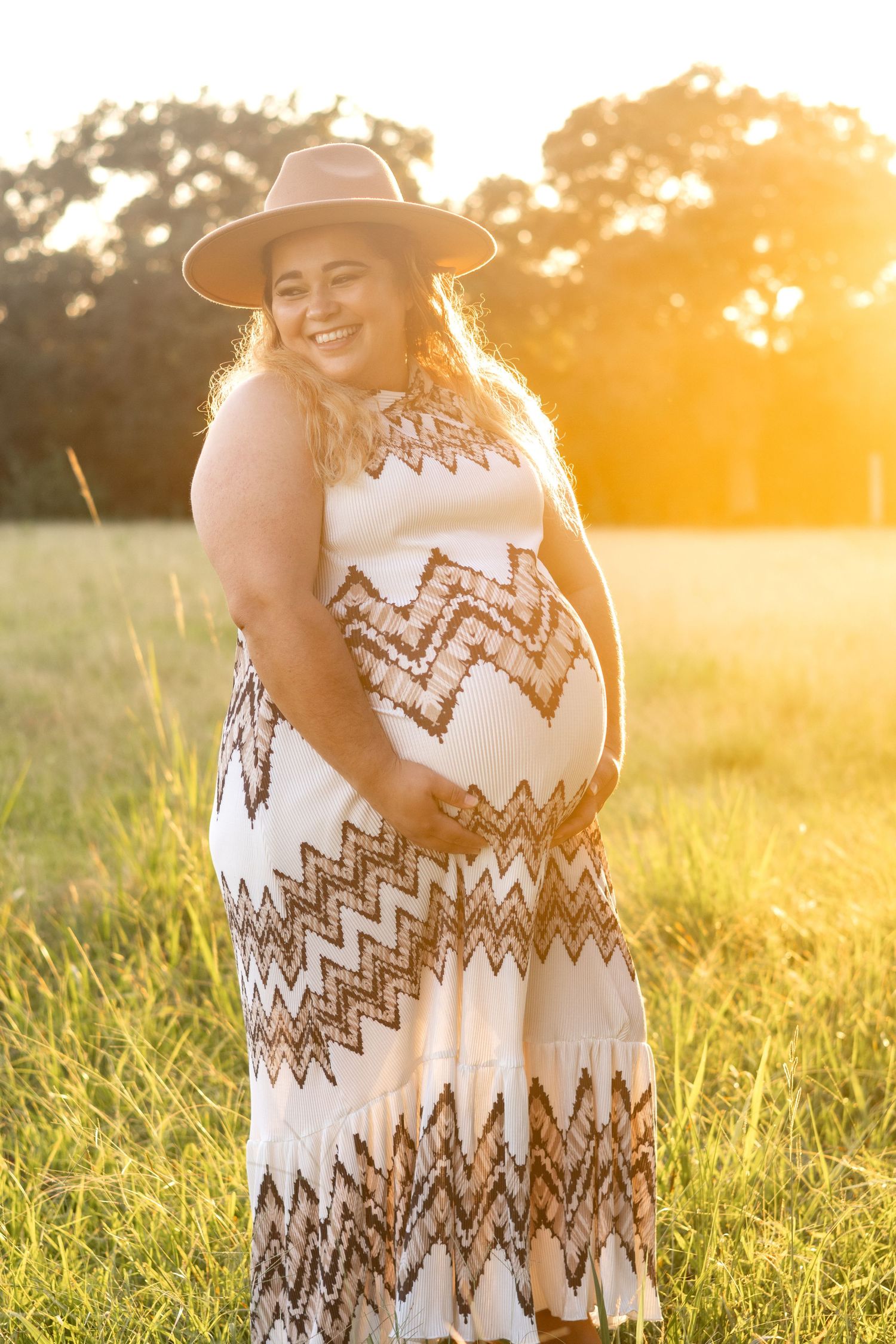 Beautiful expectant mother photographed in golden sunlit field.
